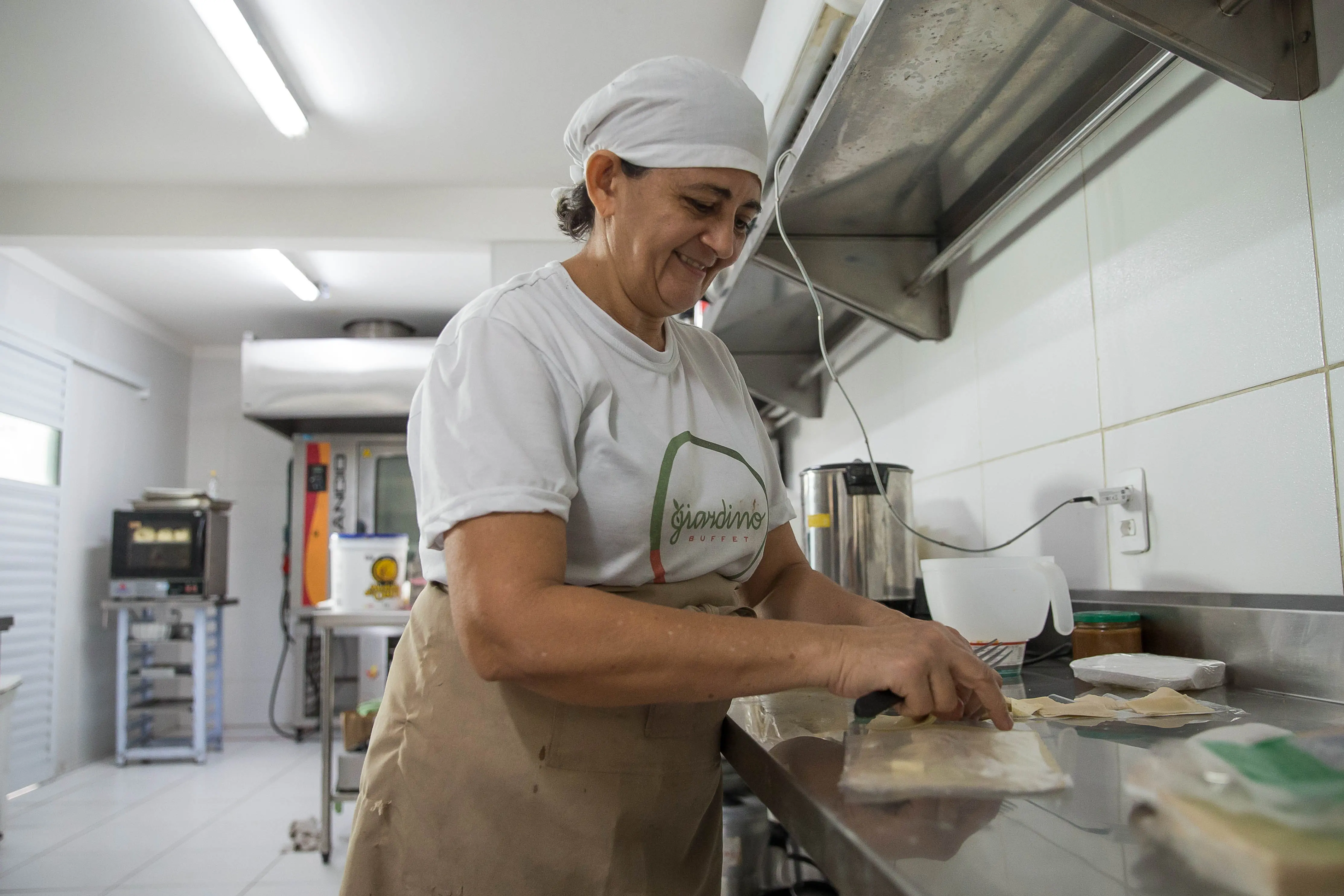 Suemy Leitão manipulando massa em uma cozinha industrial