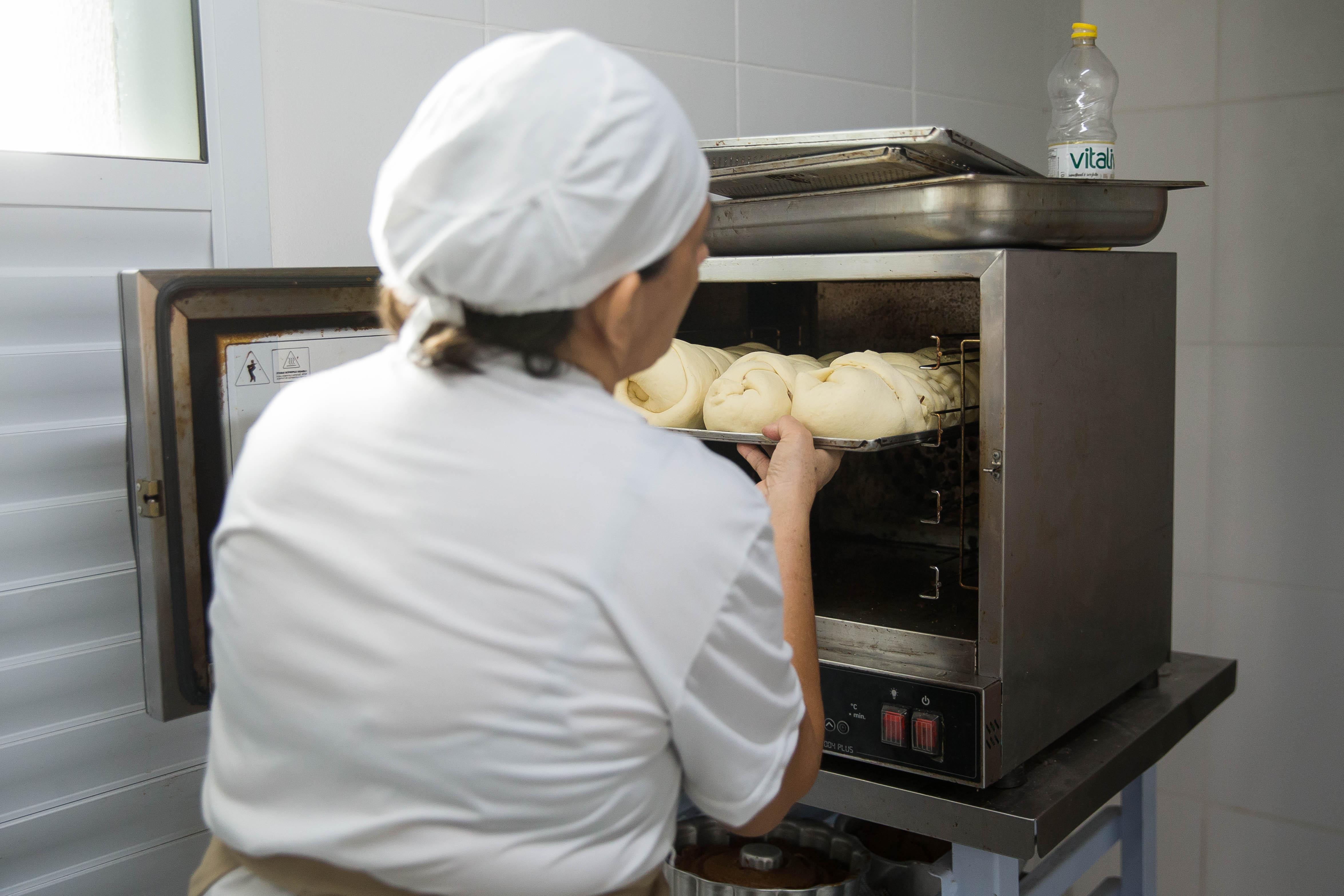 Suemy Leitão colocando massa de pão no forno