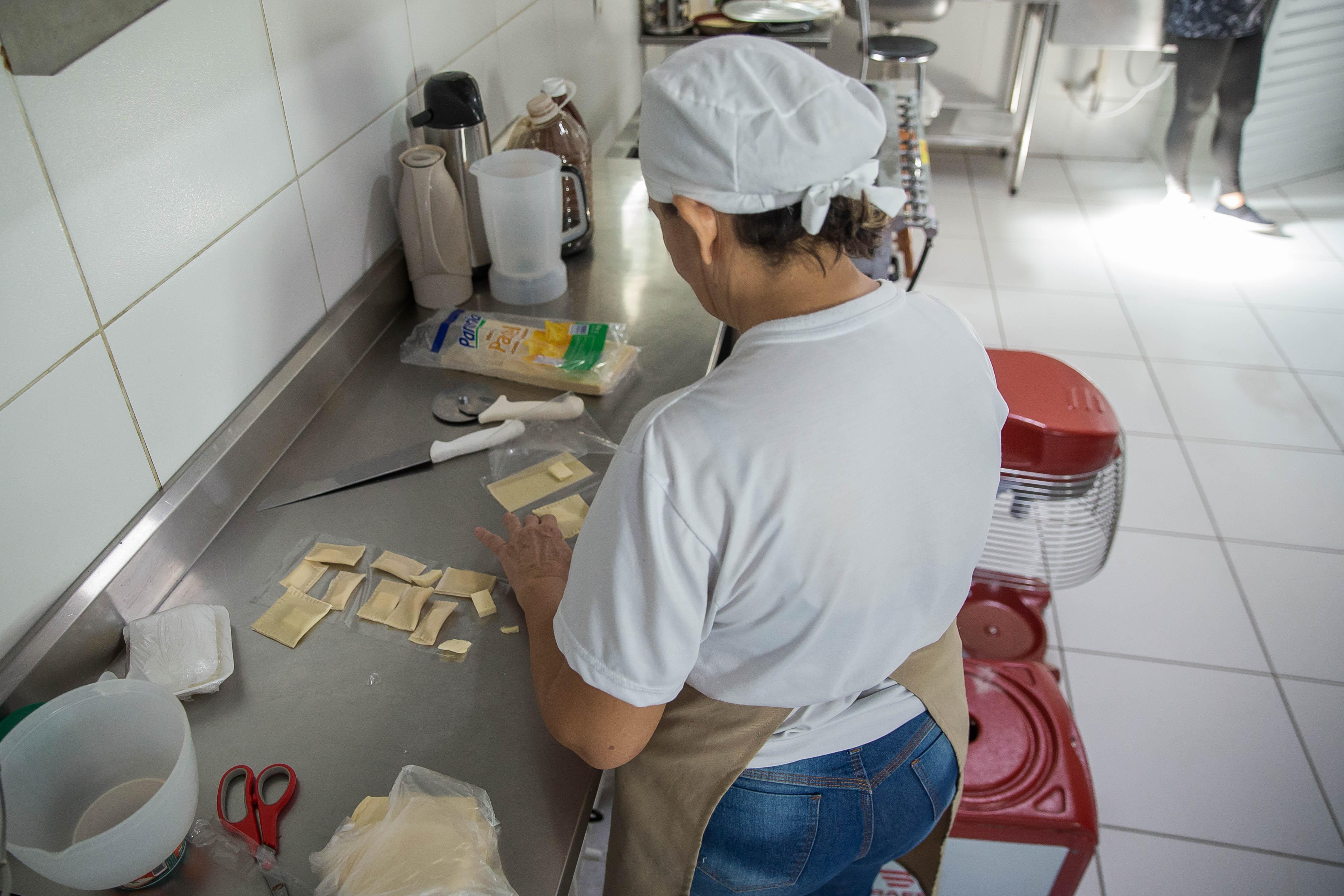 Suemy Leitão manipulando massa em uma cozinha industrial