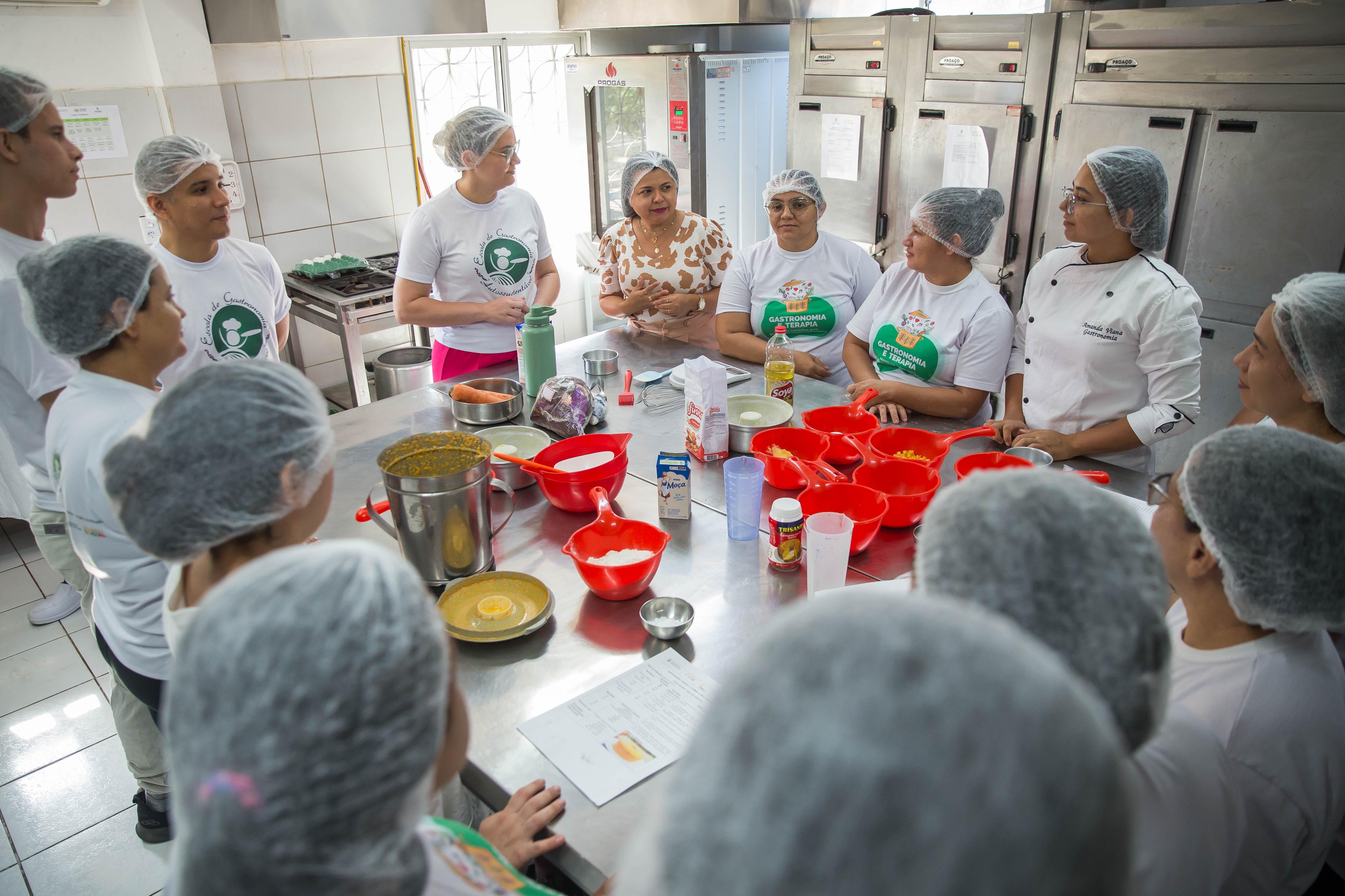 Grupo em uma cozinha industrial, com a professora ao centro explicando o conteúdo