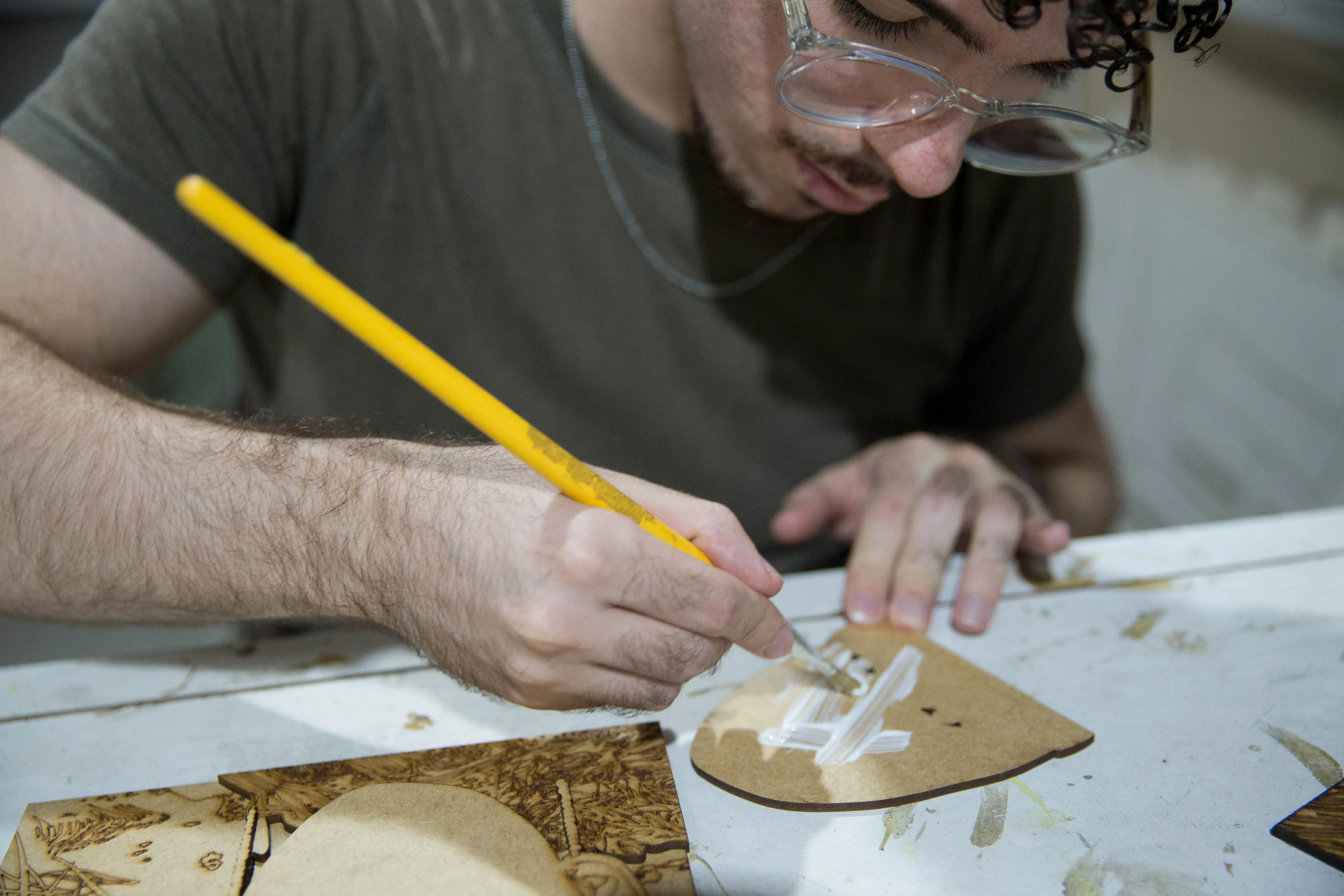 Homem passa cola no verso de uma parte da peça tátil