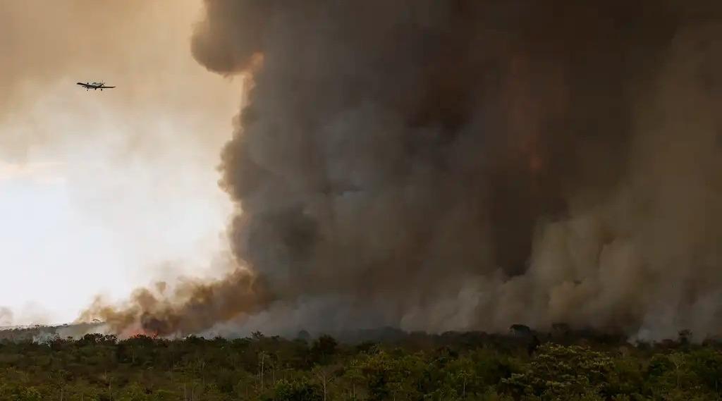 O Parque Nacional de Brasília foi atingido por um incêndio de grandes proporções. A foto mostra uma fumaça preta espessa sobre o parque e um avião se aproximando