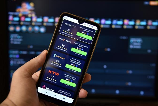 Mão segura celular aberto em frente a site de apostas esportivas