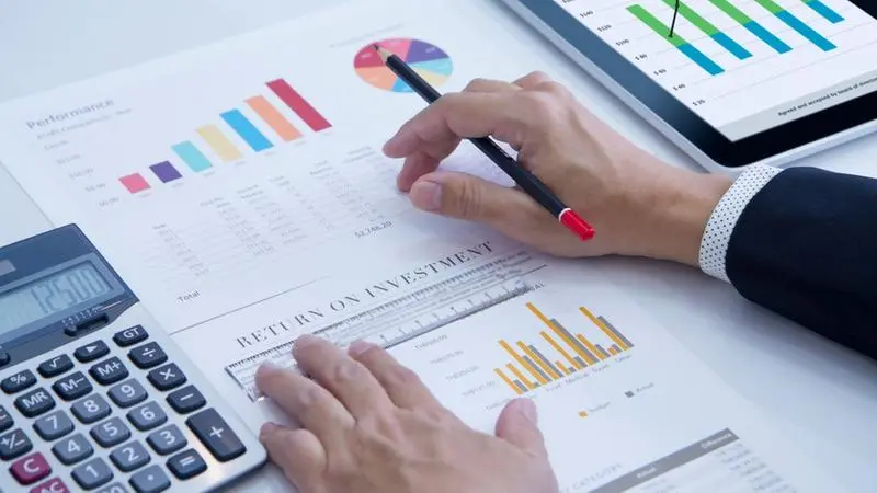 investimentos mão masculina com calculadora e gráficos