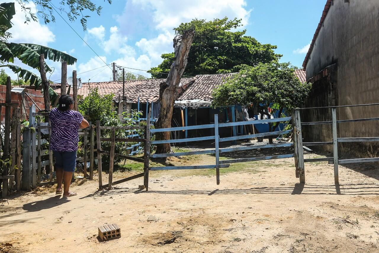 Mulher em frente à cerca de casa em terreno próximo ao campus do Pici da UFC