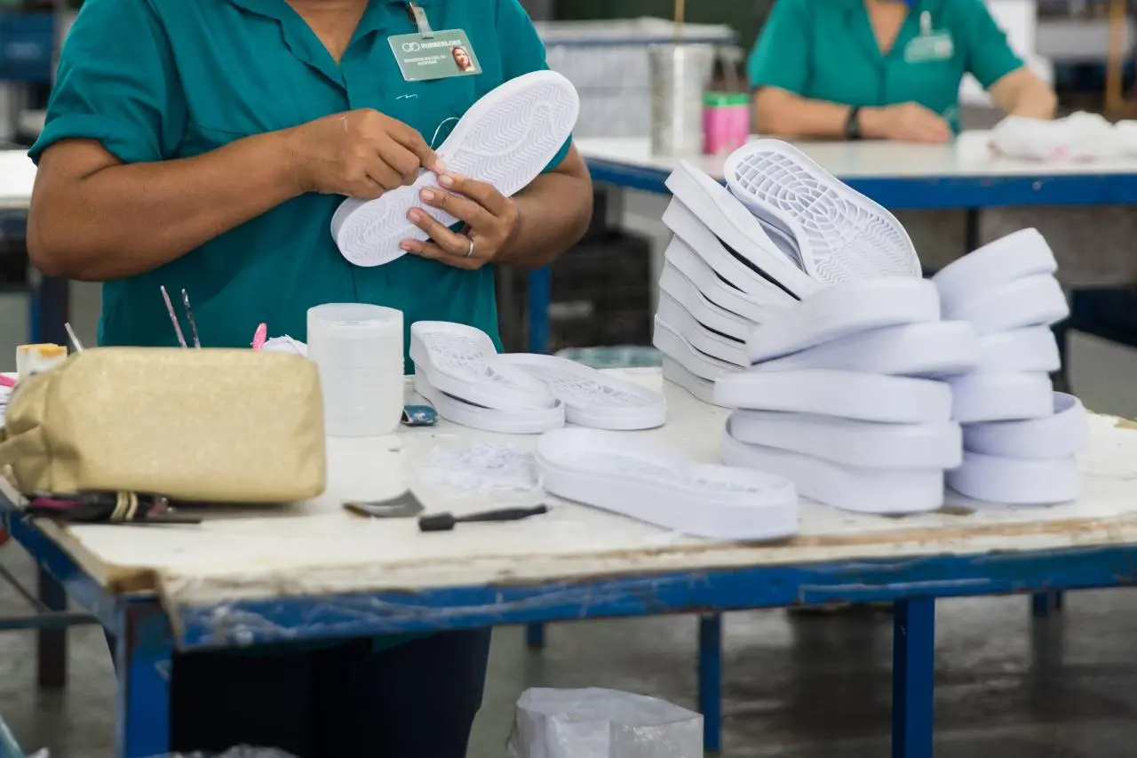 Operária manuseando calçados em fábrica do Ceará