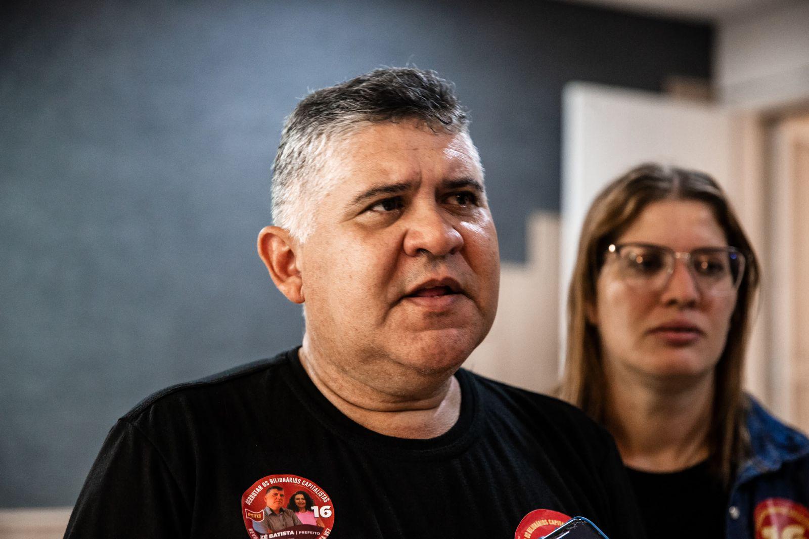 Zé Batista é um homem branco de cabelo grisalho curto. Na foto, ele está de camiseta preta