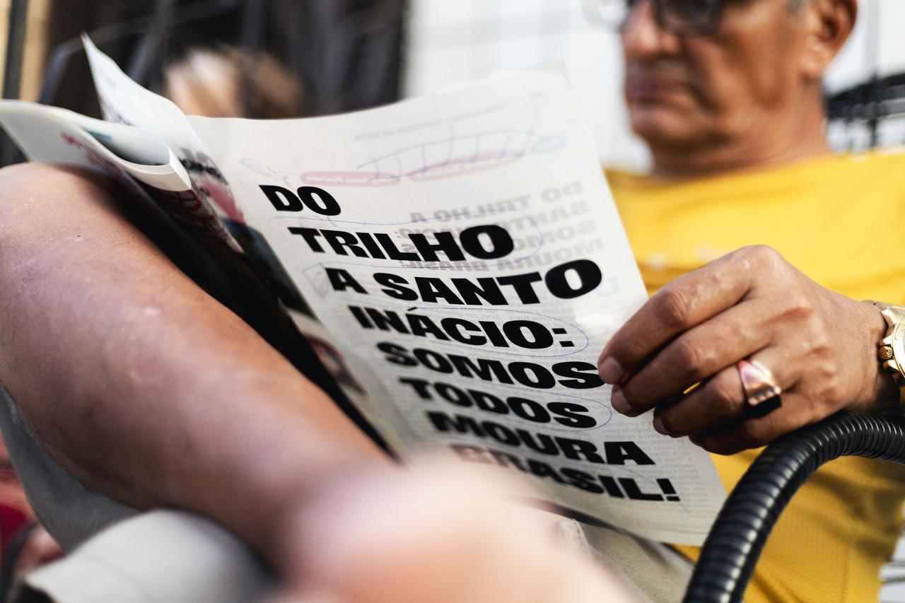 Homem lendo jornal comunitário