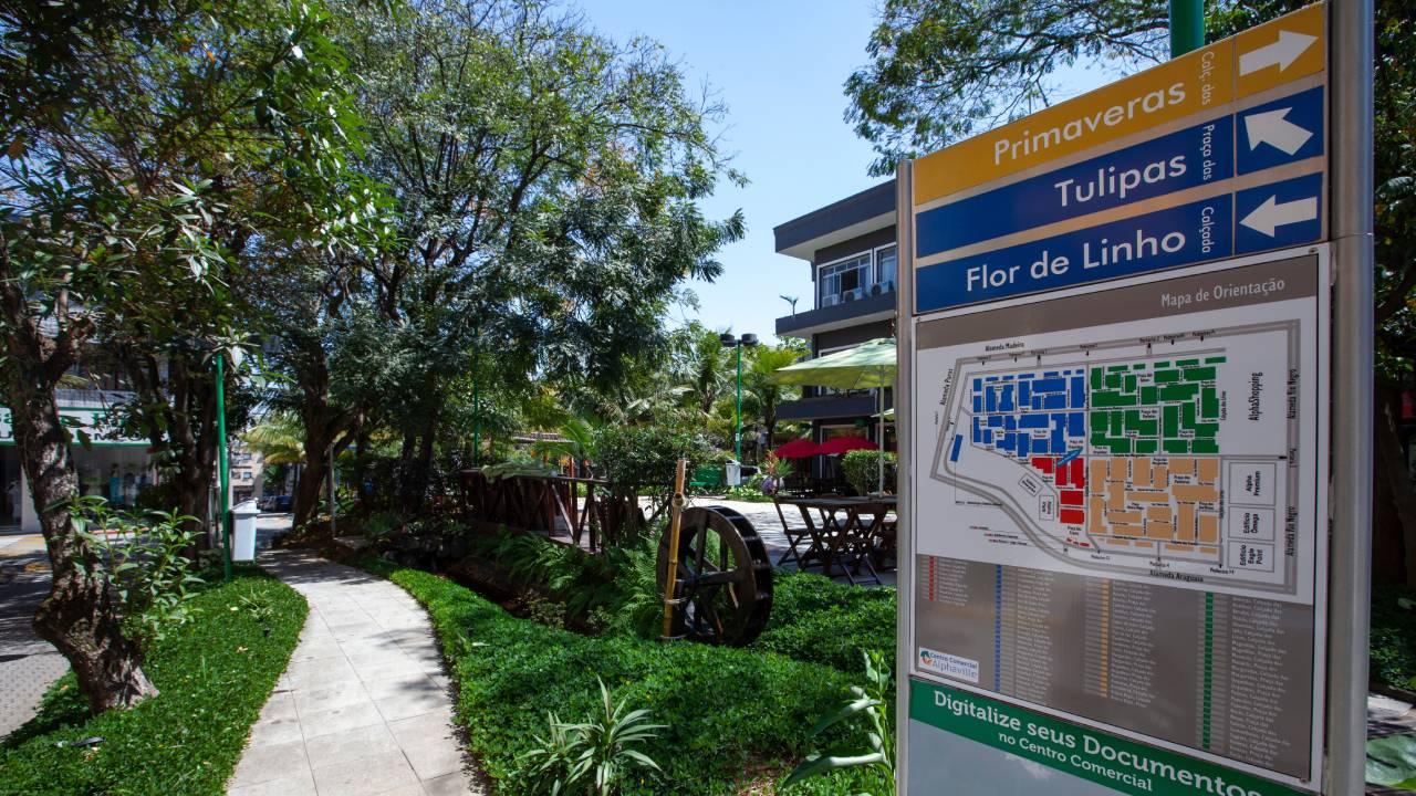 Caminho em área de convivência de condomínio fechado e placa com mapa do loteamento