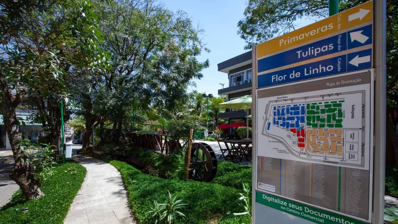 Caminho em área de convivência de condomínio fechado e placa com mapa do loteamento