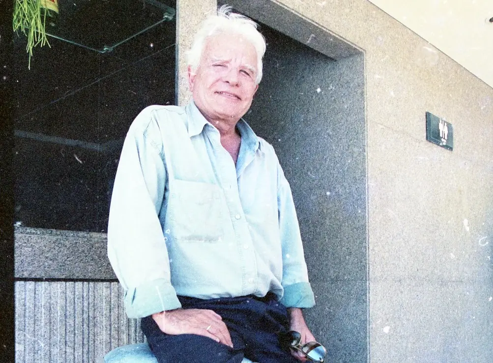 Cid Moreira é um homem idoso branco e de cabelos também brancos. Na foto, ele está de camisa azul de botão