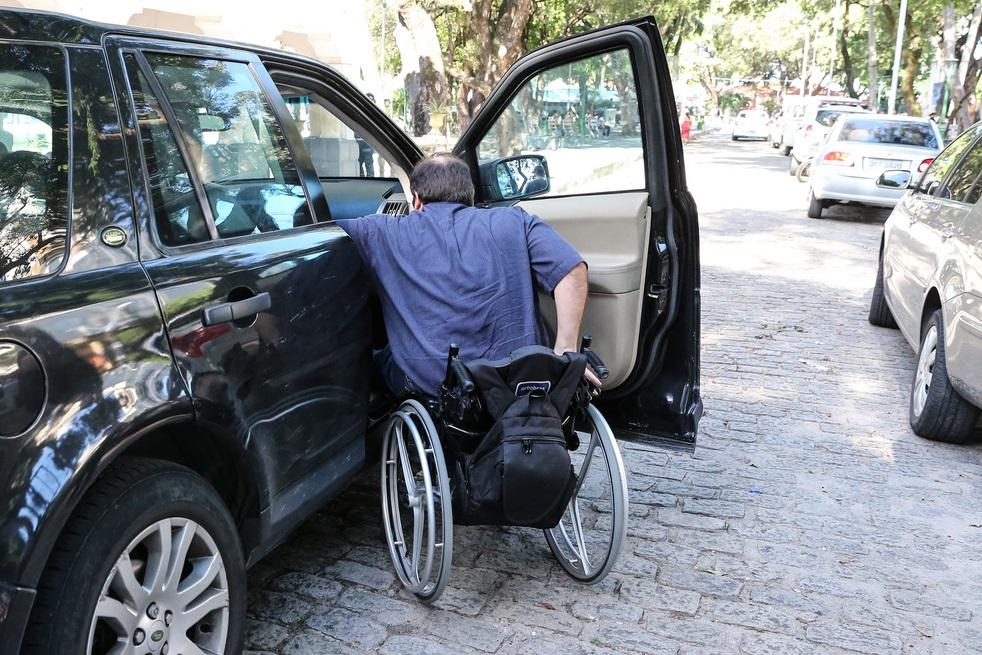 Homem em cadeira de rodas se prepara para entrar em carro