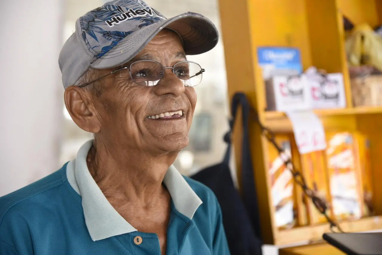 Idoso sorrindo usando boné e óculos de grau