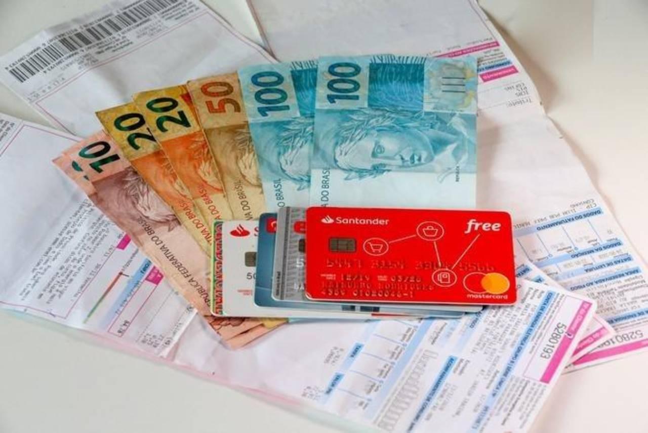 Contas, dinheiro e cartões de crédito sobre uma mesa