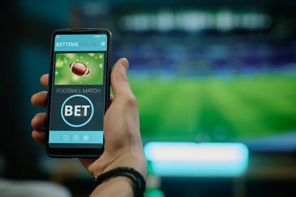 Mão segura celular aberto em plataforma de bets