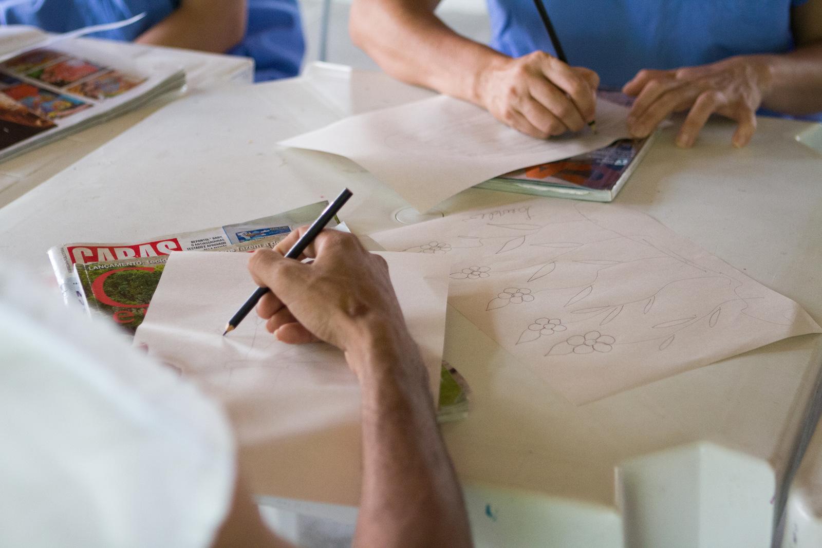 Mãos desenhando no papel de lápis