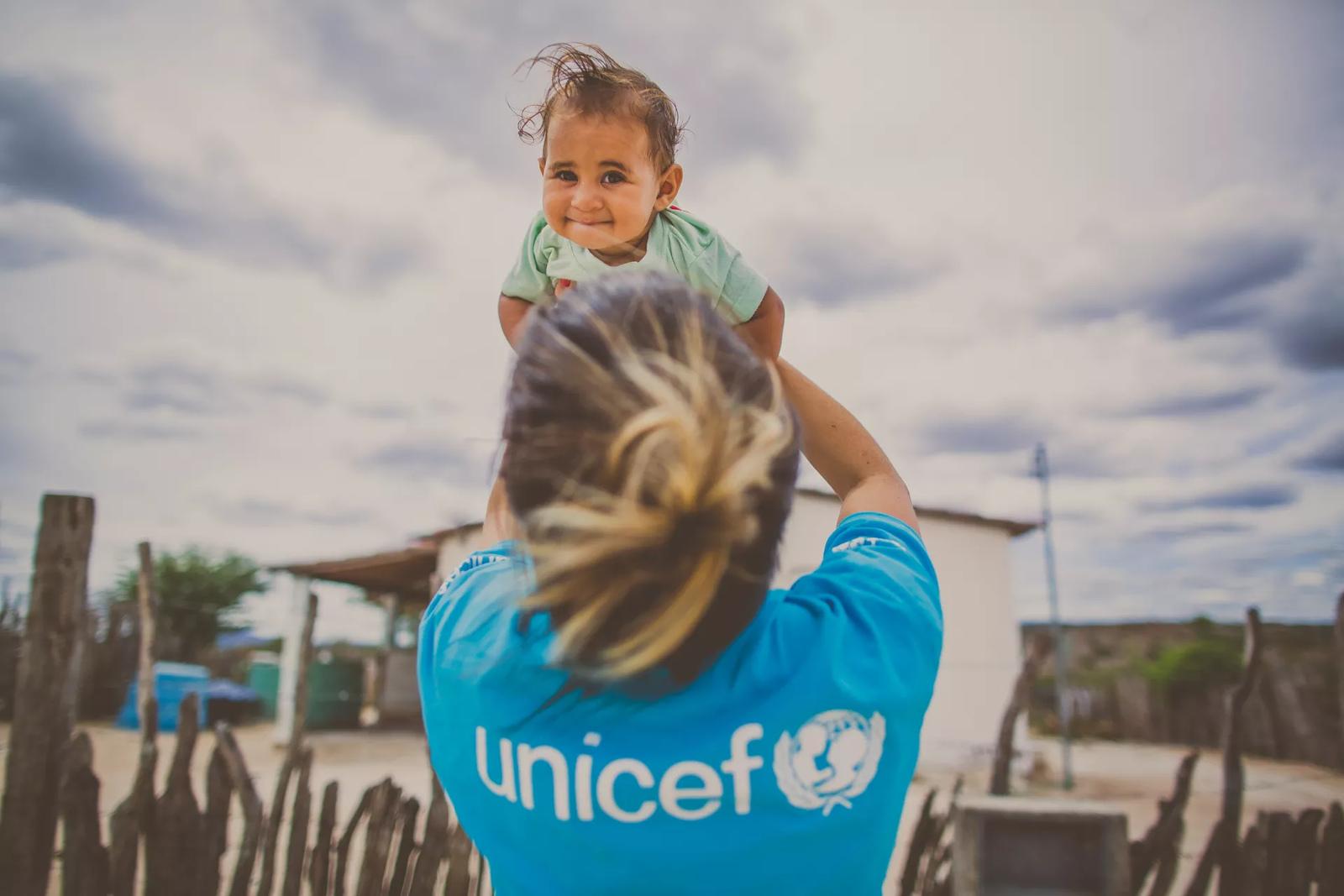 Agente do Unicef ergue bebê nos braços