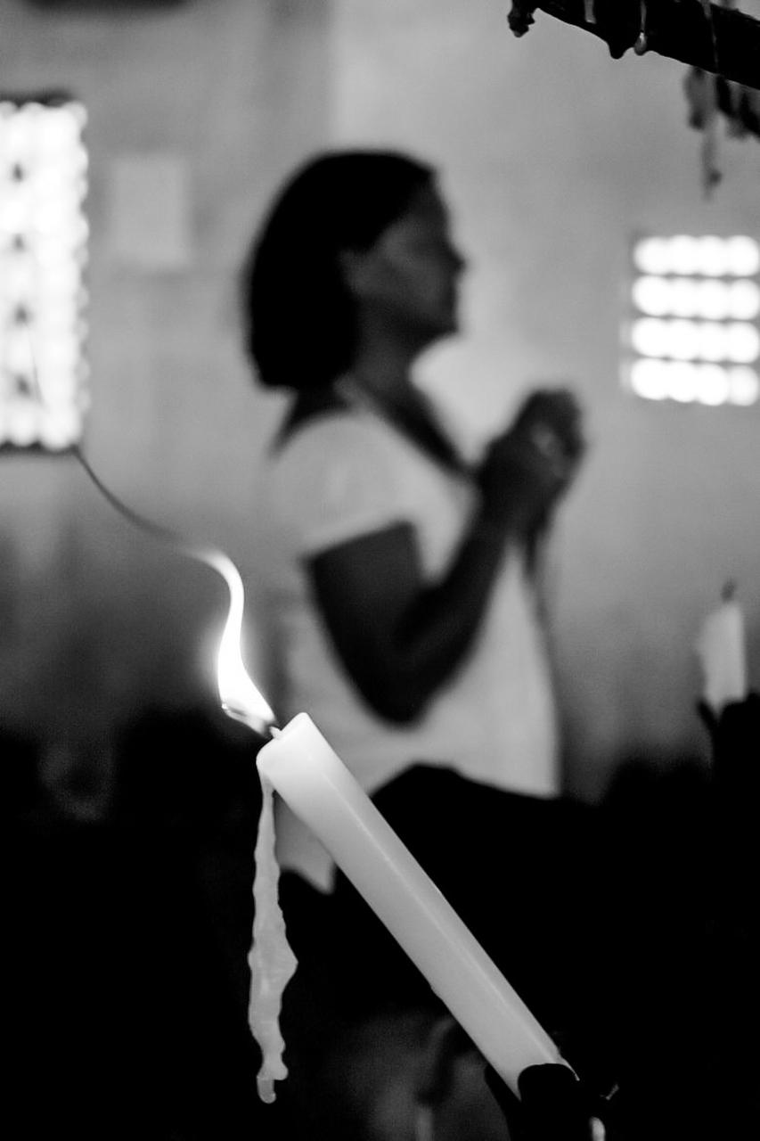 Imagem em preto e branco de mulher rezando 