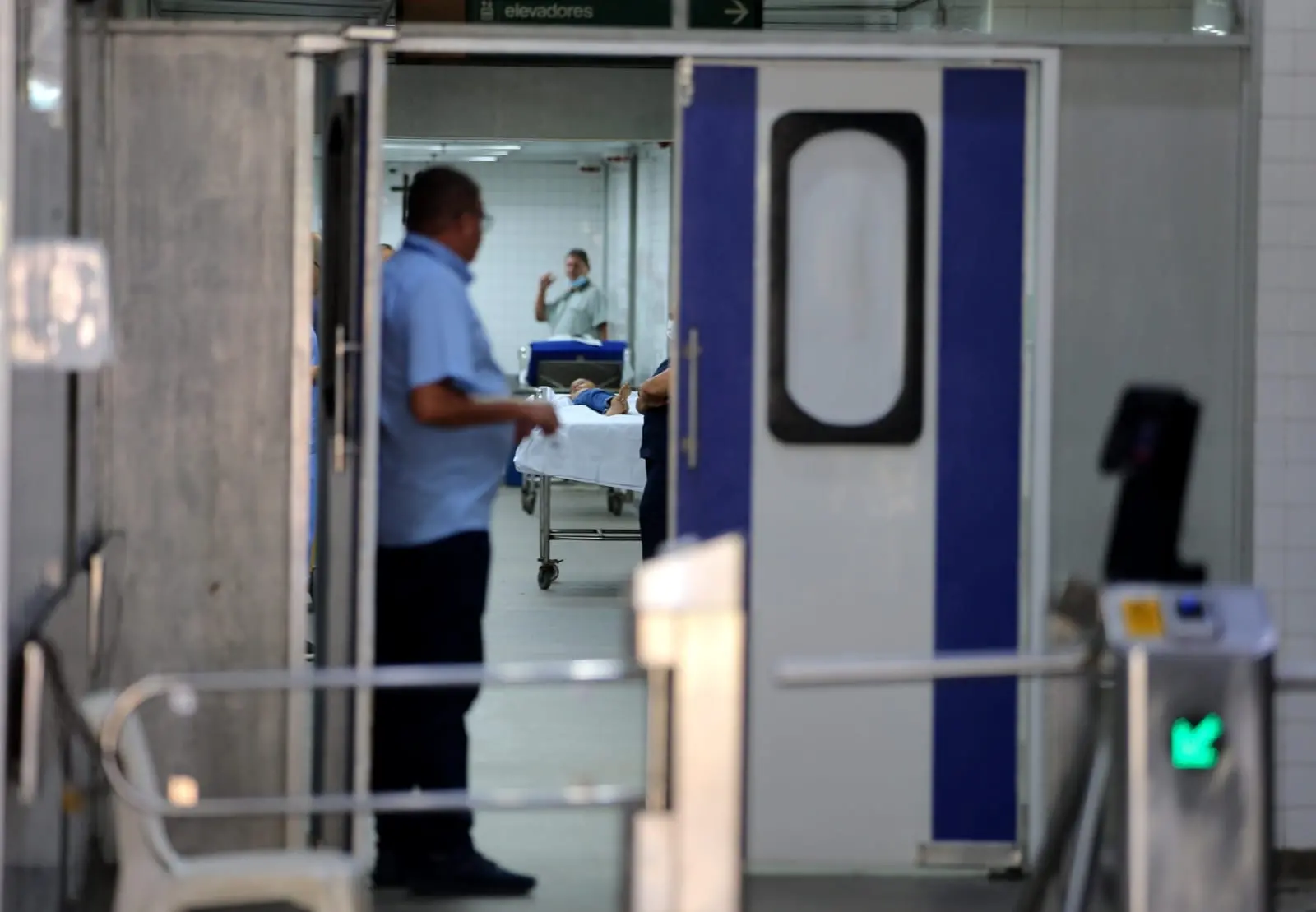 Porta de hospital entreaberta mostra paciente em corredor
