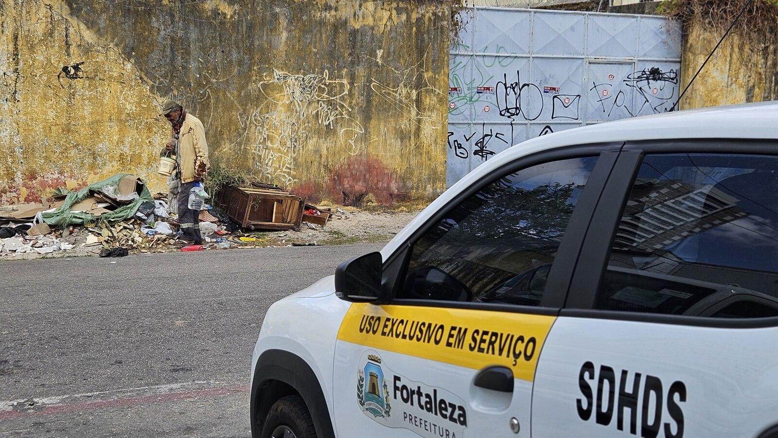 Pessoa em situação de rua ao lado de carro da SDHDS