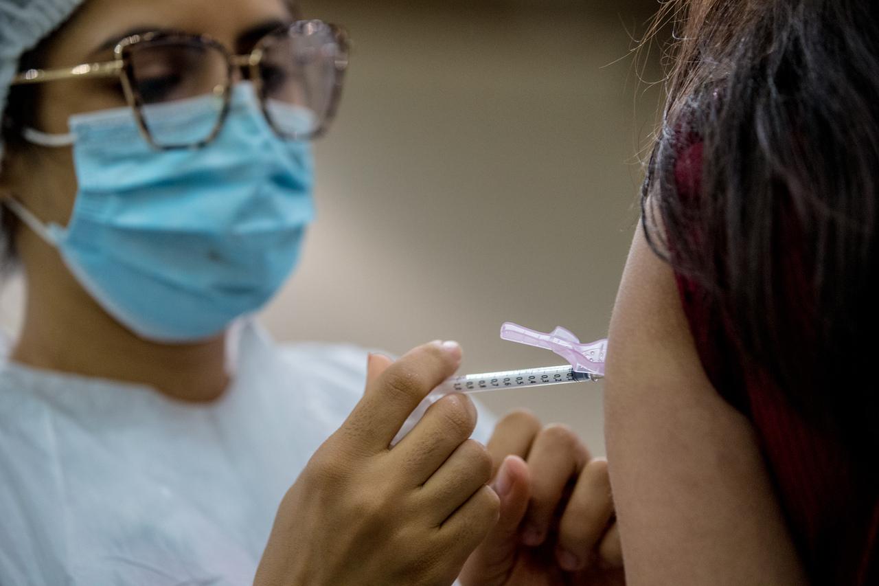 Profissional de saúde aplica vacina em mulher
