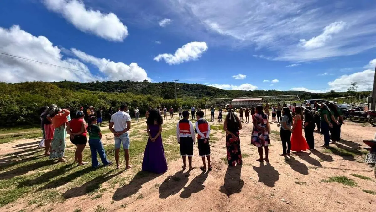 Pessoas indígenas reunidas em círculo em um campo aberto