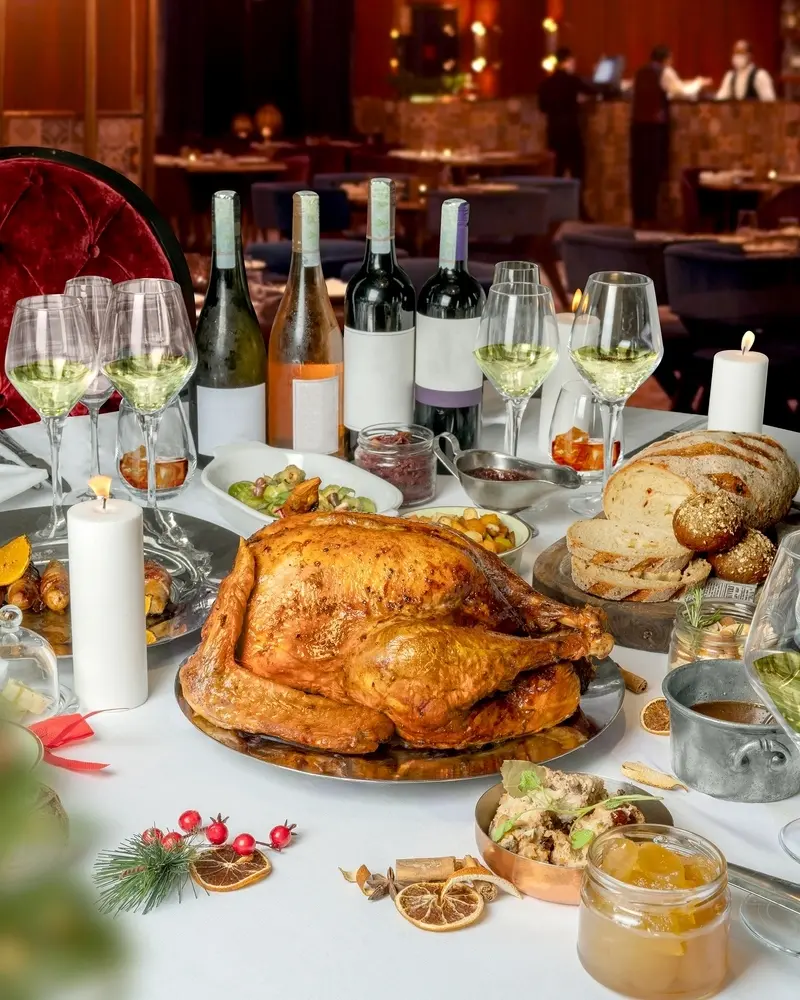 mesa preparada com taças, velas, bebidas e pratos contendo diversas comidas natalinas para ceia