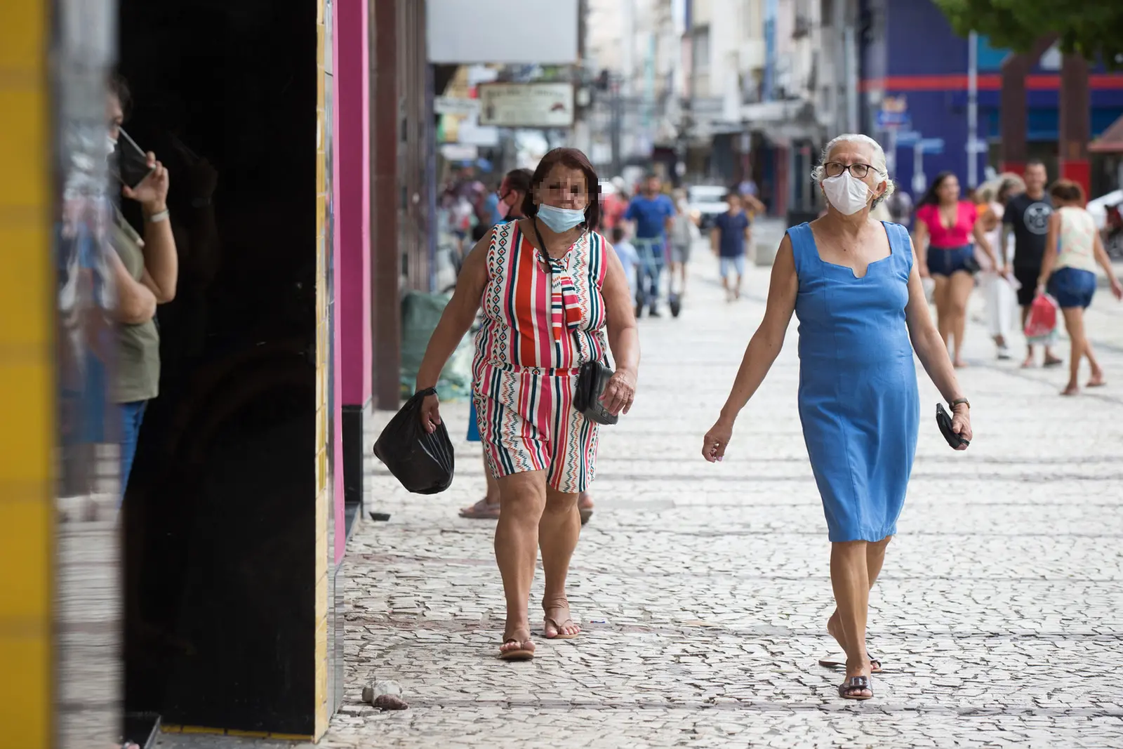 Mulheres caminhando na rua com máscara de proteção