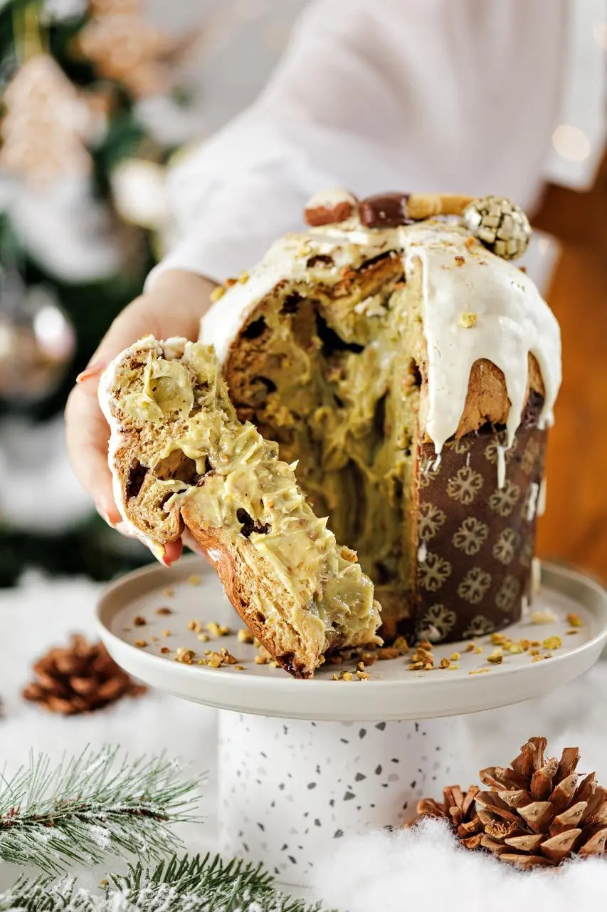 A imagem mostra uma pessoa retirando uma fatia de panetone de pistache da Cake2 para Natal em Fortaleza