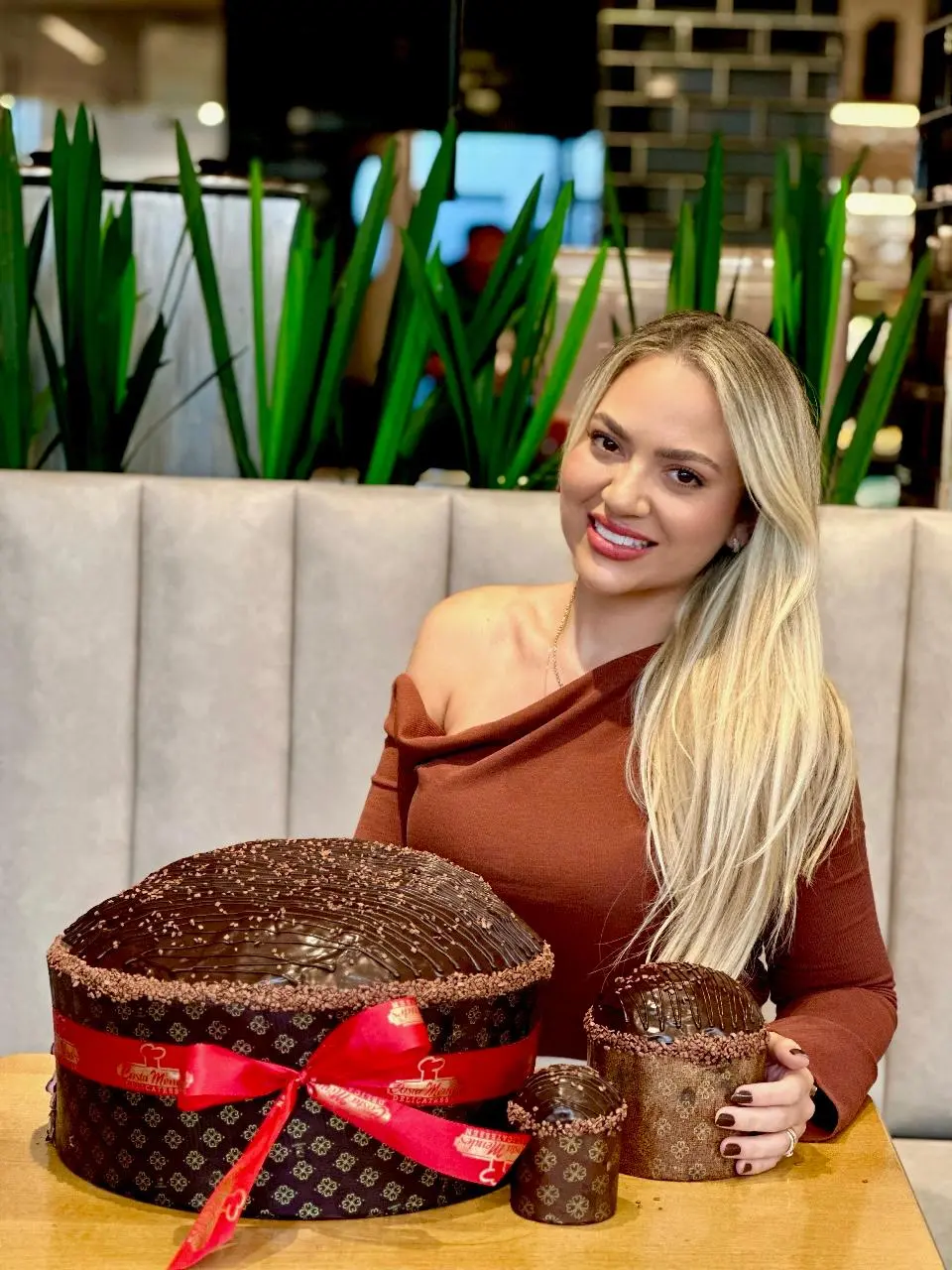 a imagem mostra uma mulher sorridente com três opções de Panetones de Chocolate Trufado da Costa Mendes para o Natal em Fortaleza