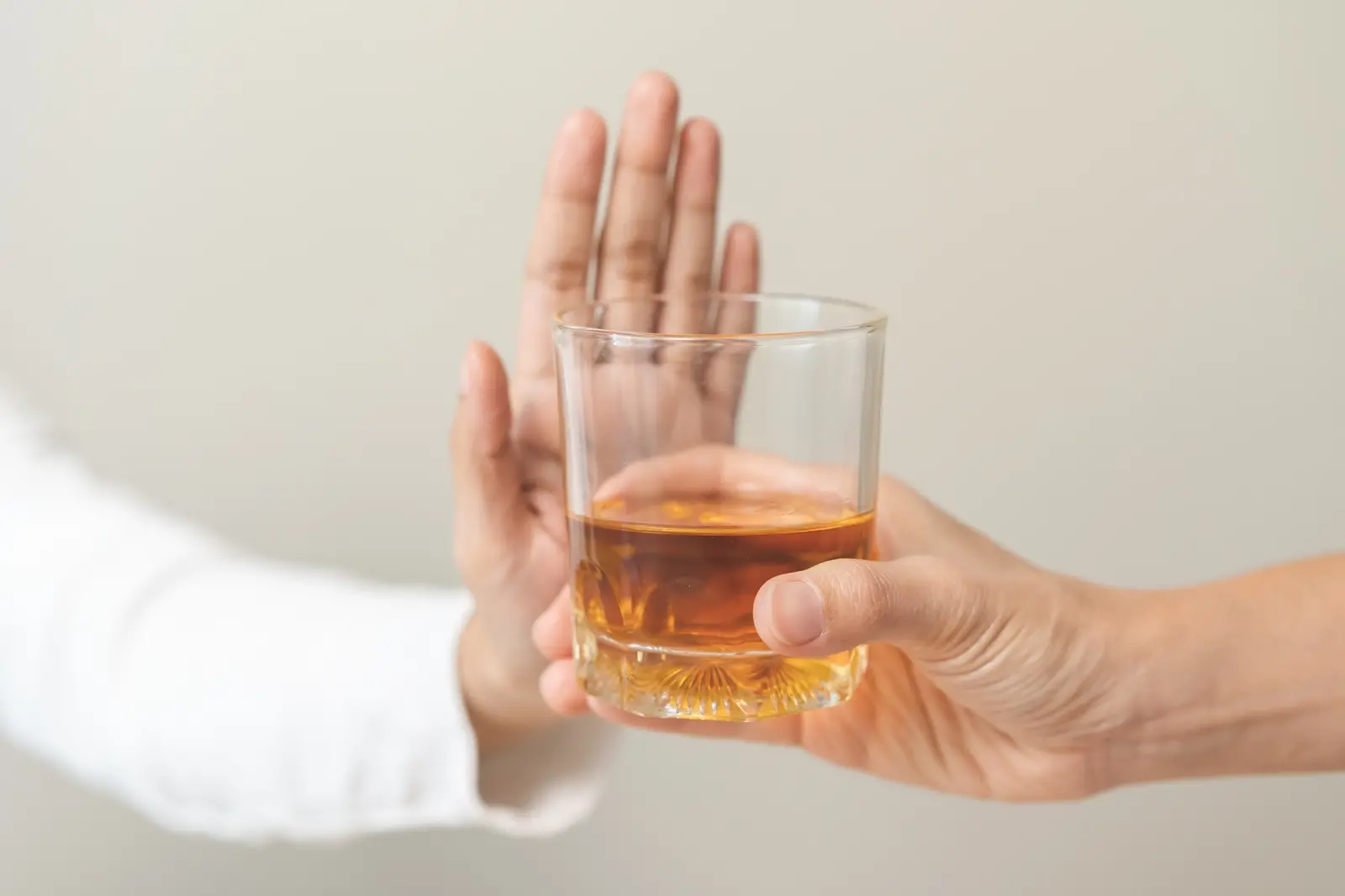 Mão recusando copo de bebida alcoólica