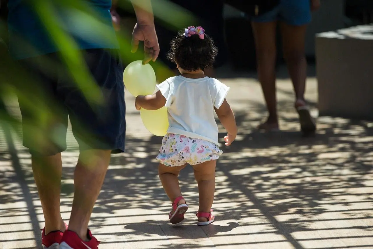 Criança caminhando ao lado de homem