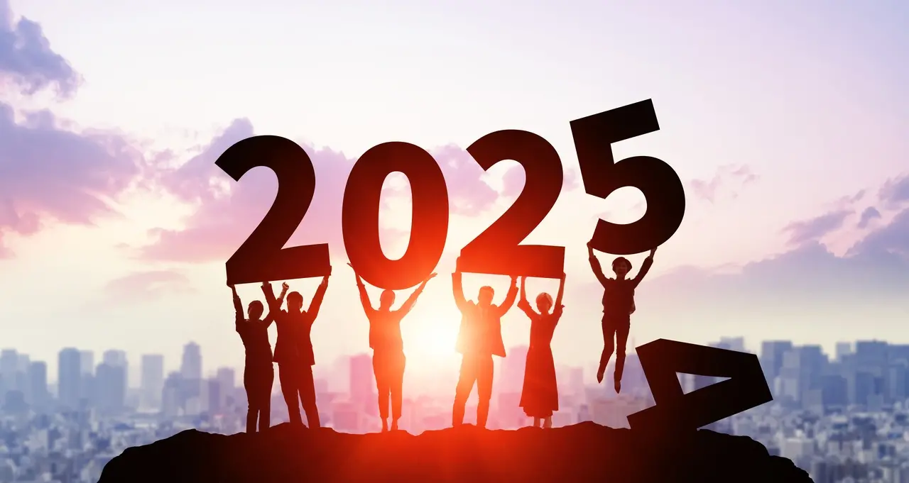 Grupo de pessoas em um morro segurando os números 2025, com um pôr do sol ao fundo. Esta imagem simboliza celebrações e novas esperanças para o futuro.