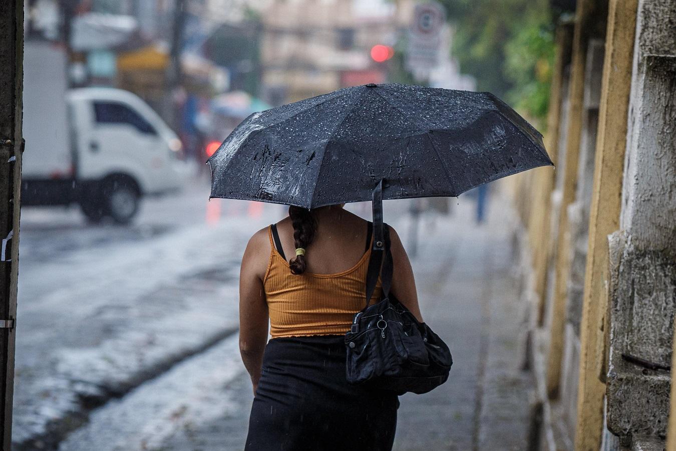 Mulher de costas com guarda-chuva preto na mão