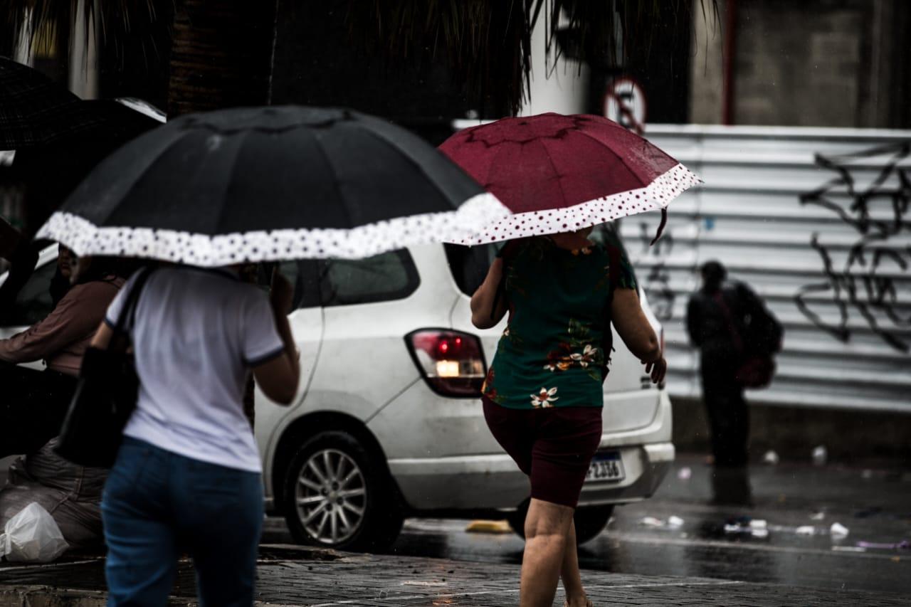 Dia chuvoso em Fortaleza e pessoas usando guarda-chuvas