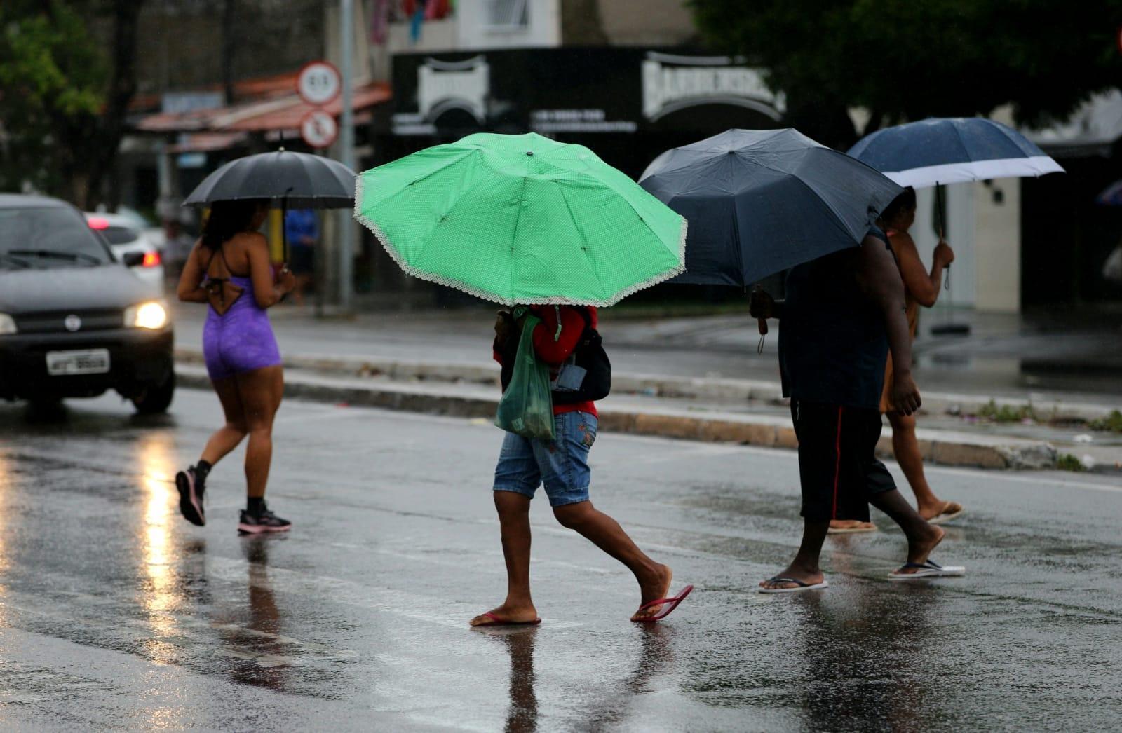 Pessoas caminhando com guarda chuva