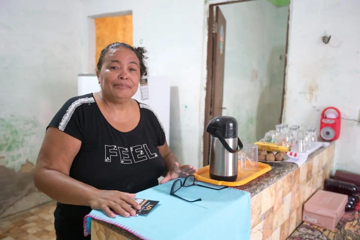 Márcia com camisa preta em frente ao muro amarelo