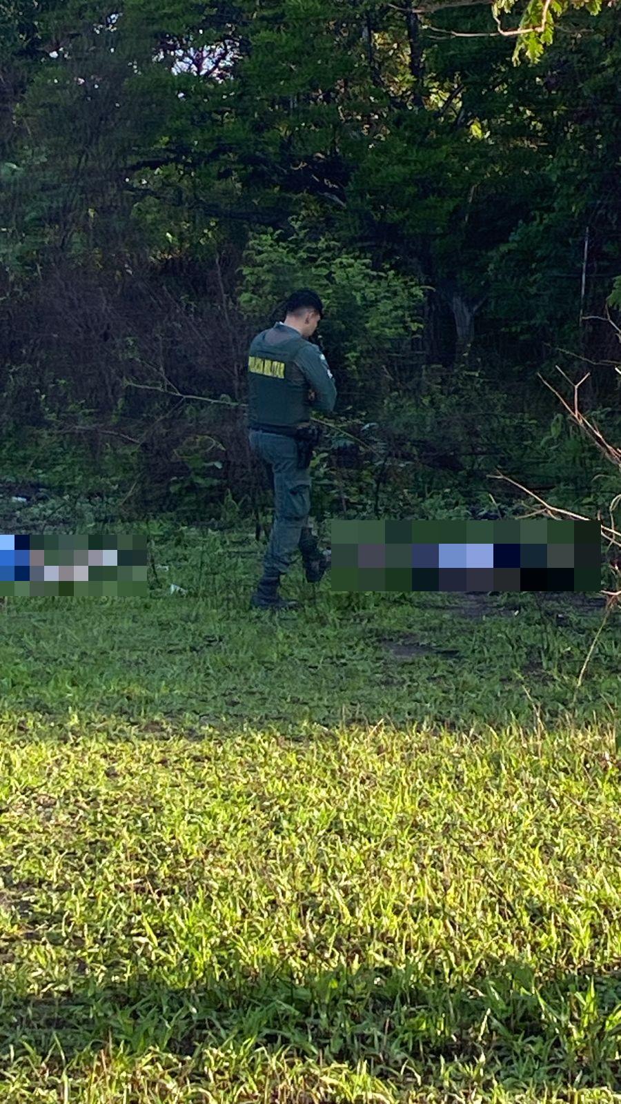Foto de policial militar ao lado dos corpos de dois homens encontrados mortos no bairro Mondubim, em Fortaleza