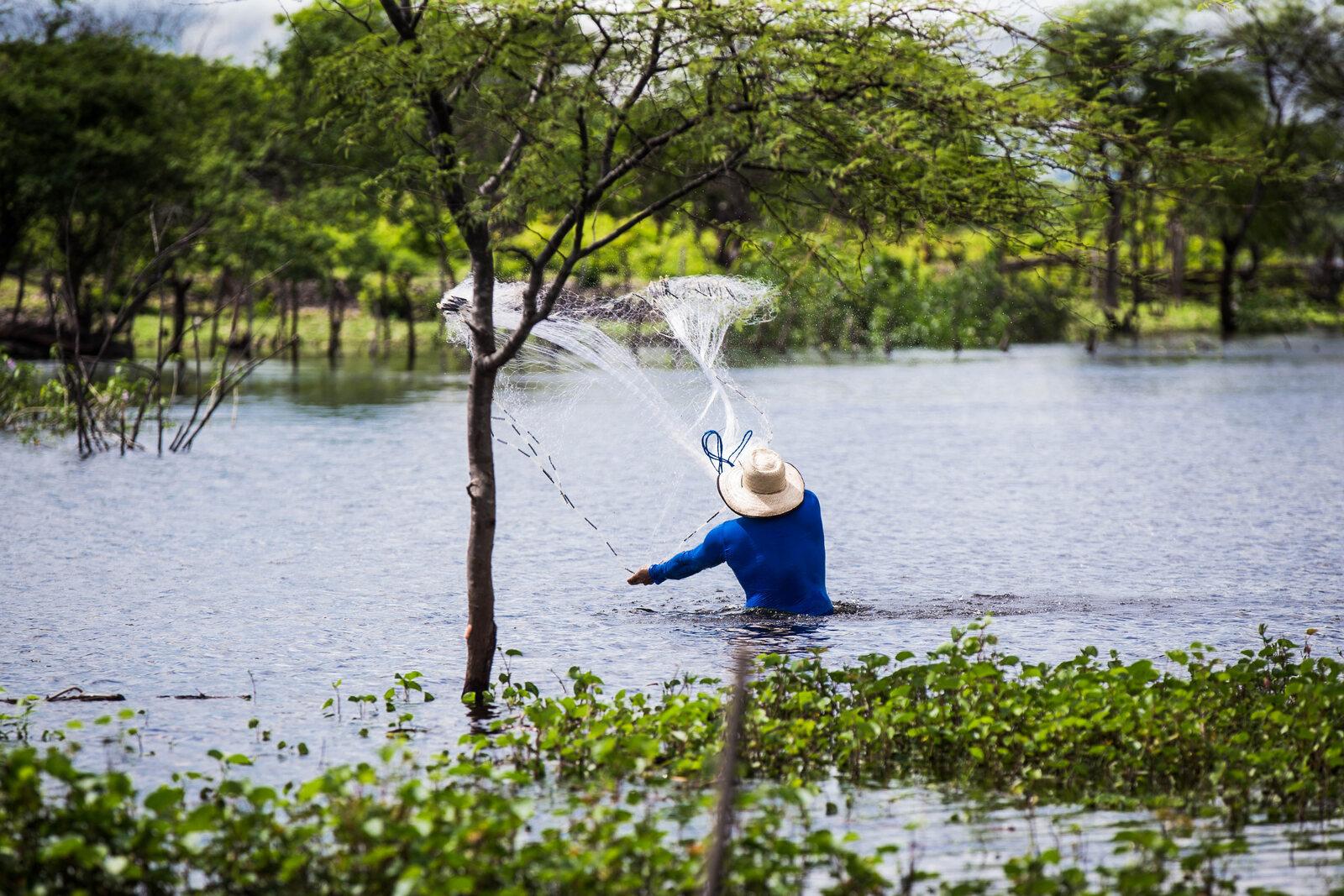 Homem jogando rede de pesca no Açude Patos, no interior do Ceará