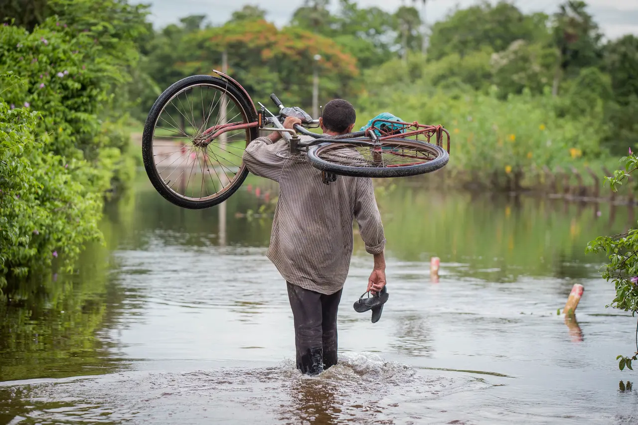 Homem entra na água com bicicleta nas costas