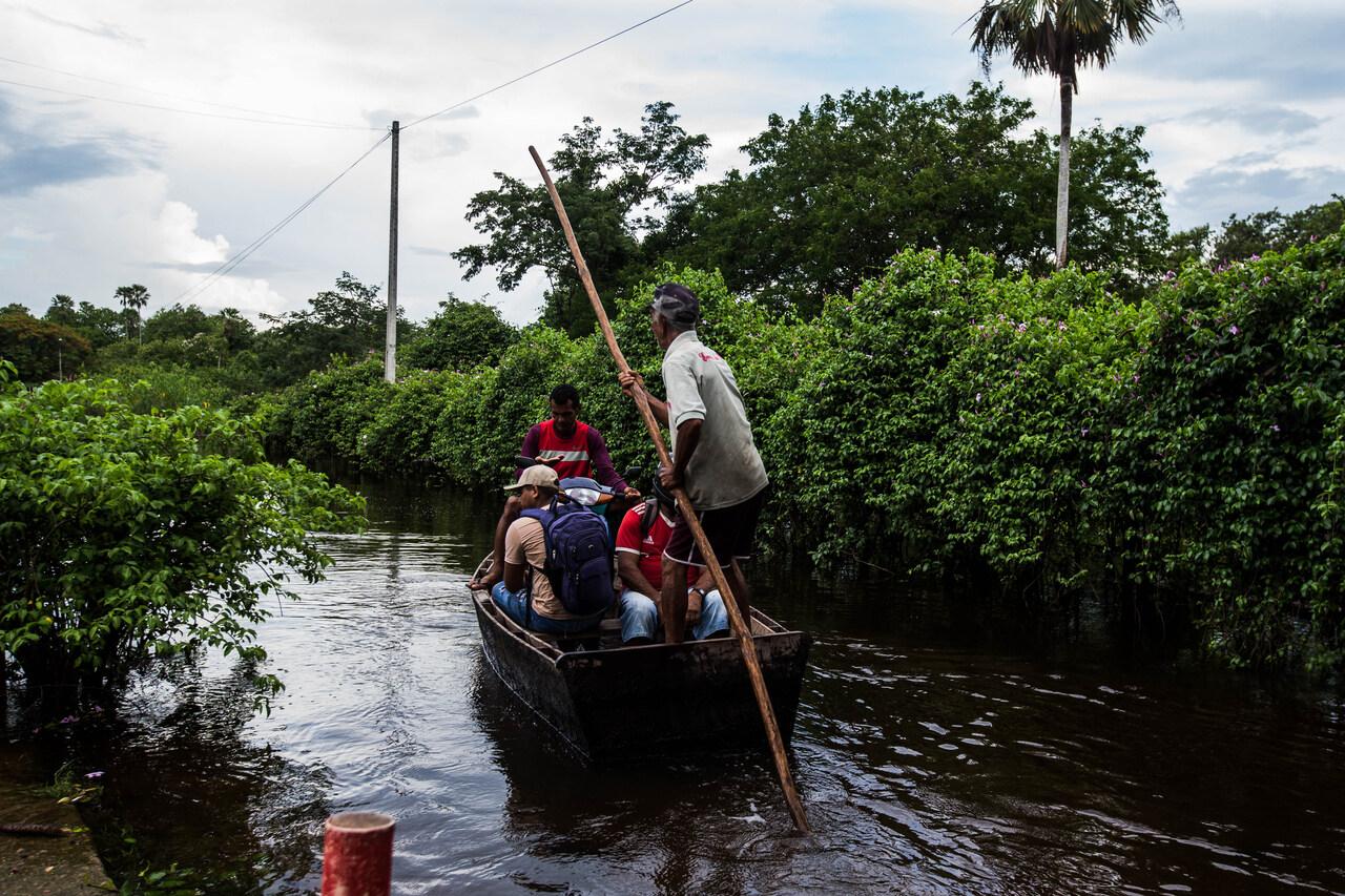 Barqueiros levam homens dentro de canoa