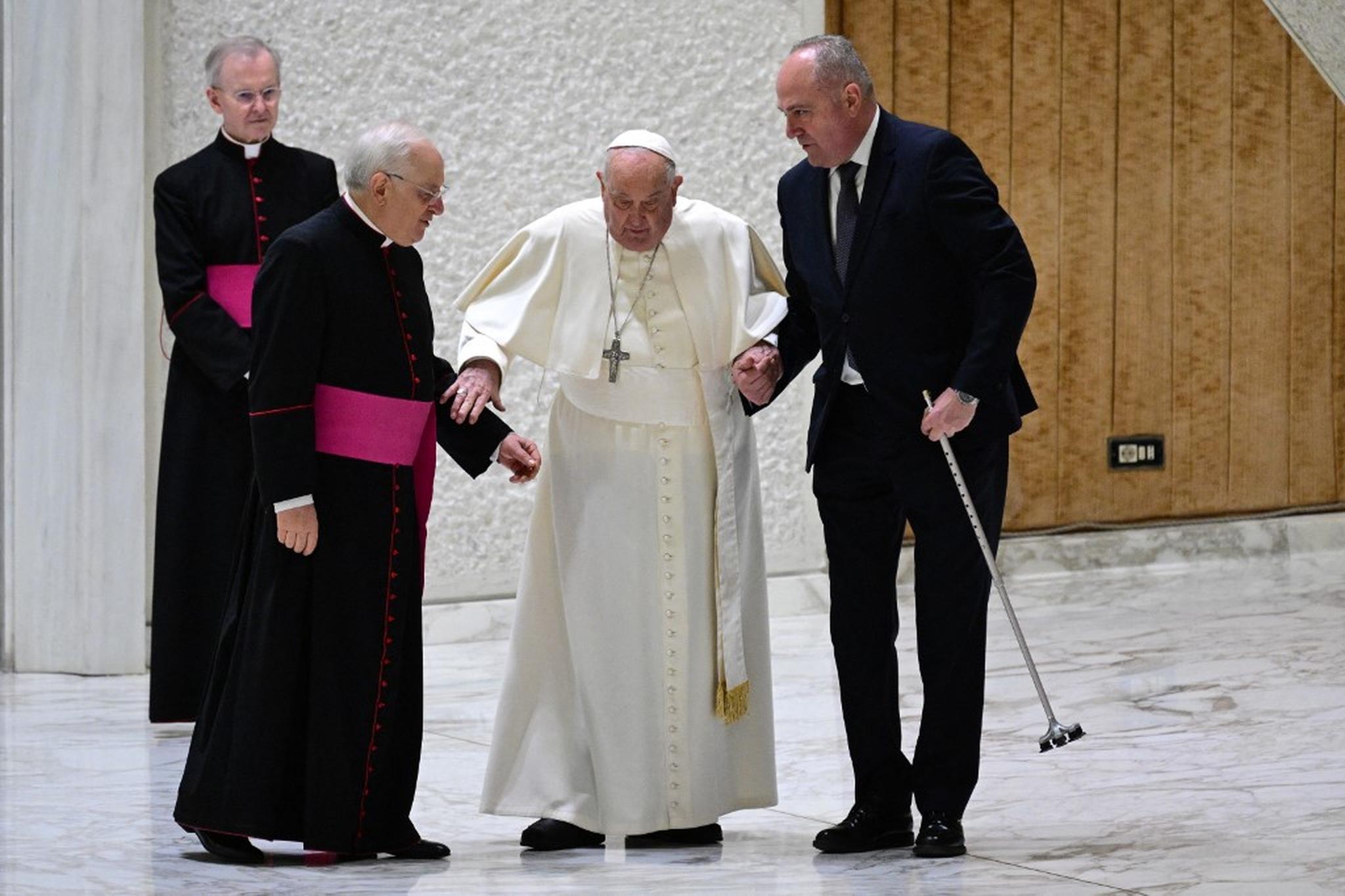 Papa Francisco recebe ajuda de dois auxiliares após o cabo de sua bengala quebrar e ele tropeçar