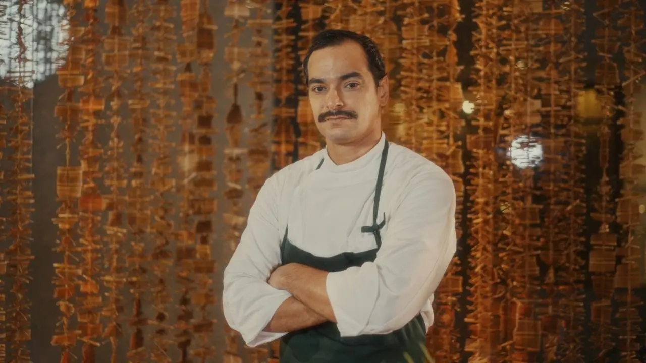 Foto de Flávio Rodrigues, homem branco de bigode com uniforme de chef de cozinha