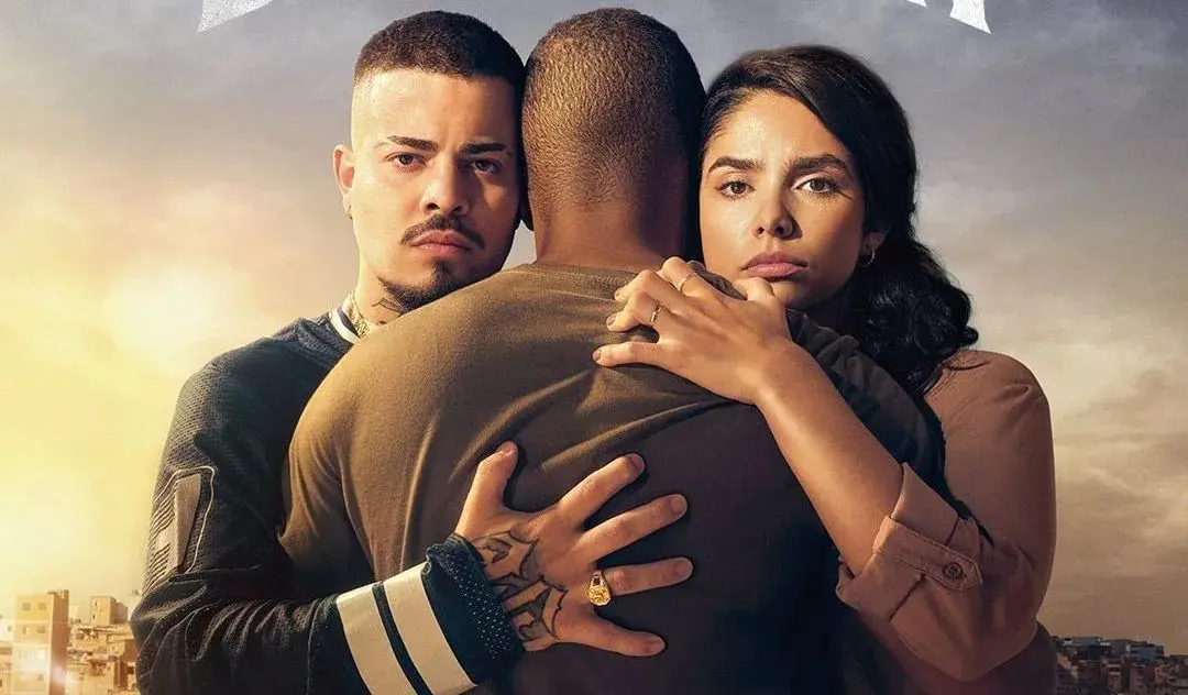 Cena dramática de Dino, Rita e Nando se abraçando, expressando emoções intensas, com fundo da cidade ao entardecer.