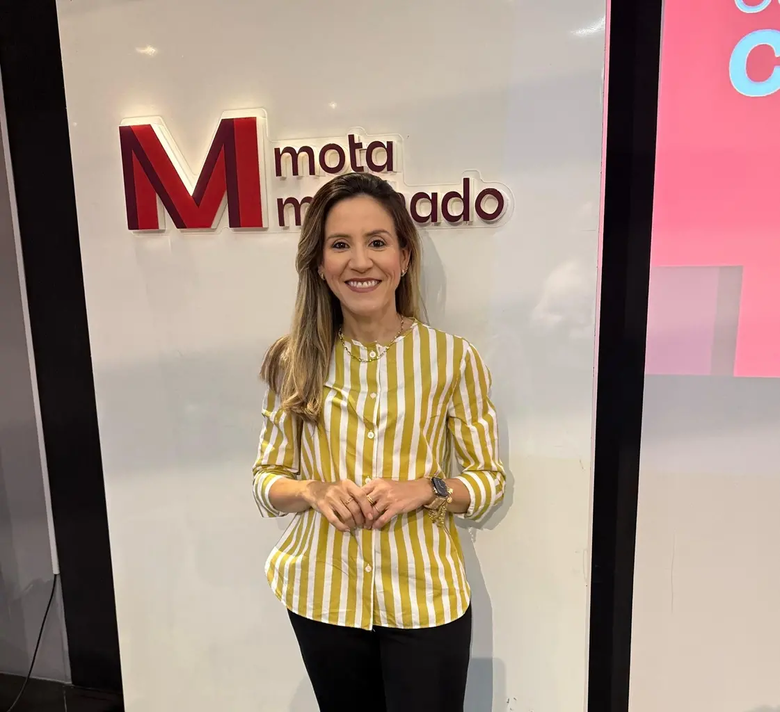 Mulher branca de camisa amarela listrada posa para a câmera