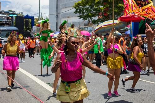 Foto de cenário vibrante de carnaval com foliões dançando em trajes coloridos.