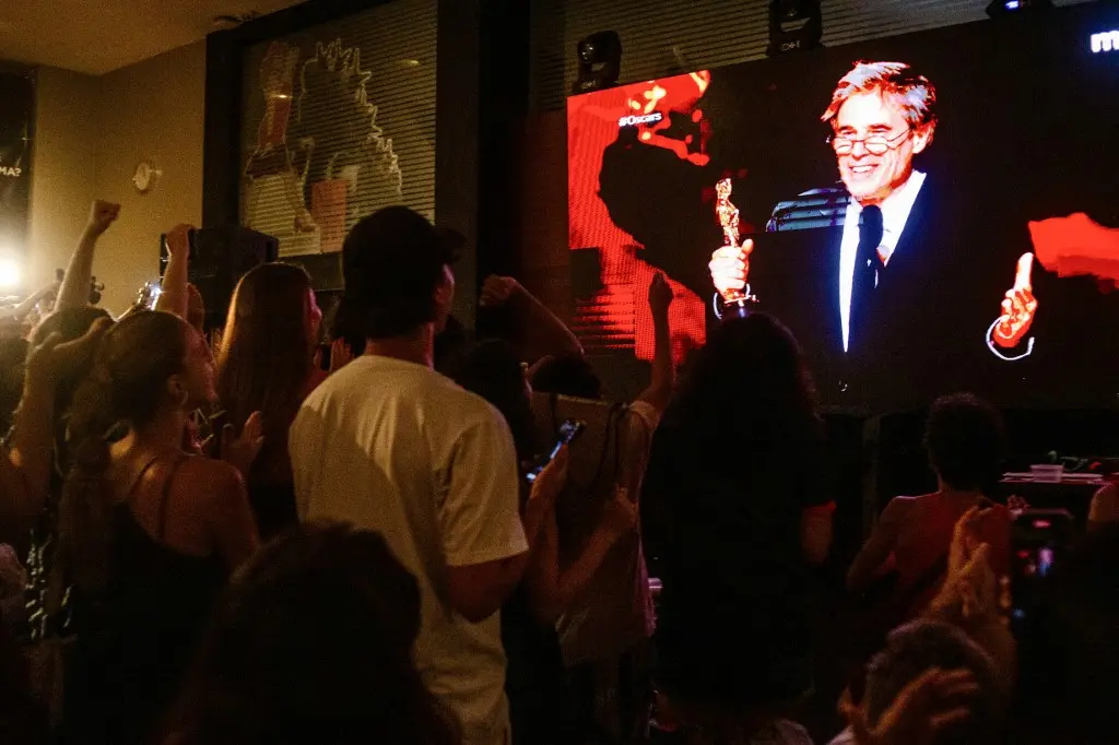 Uma plateia assiste à transmissão do Oscar de 2025 enquanto o diretor Walter Salles faz o discurso após vencer a categoria Melhor Filme Internacional com o longa 