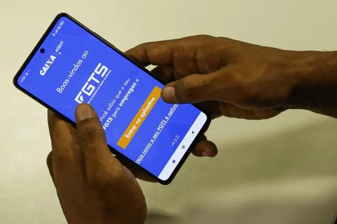 A imagem mostra um celular acessando o aplicativo do FGTS, que é canal oficial de informações referentes ao saque-aniversário