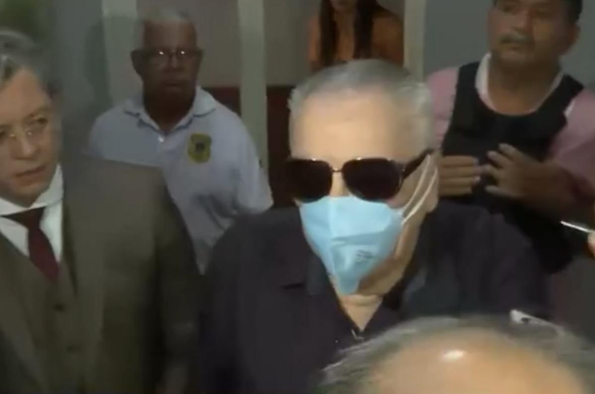 O acusado é um homem branco idoso de cabelo grisalho. Na foto, ele está de máscara azul e óculos escuros