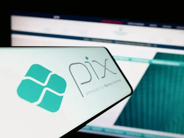 Pix aberto em um celular ao lado de tela de computador